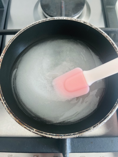 sugar and water in a pan stirring with a pink spatula