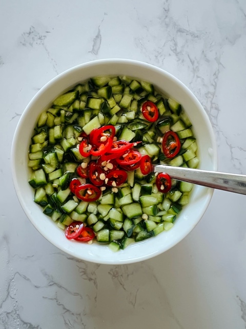 Cucumber dipping sauce in white bowl on marble background