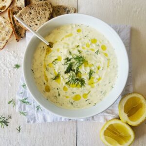Tzatziki Dip in white bowl with lemon cheeks and crackers