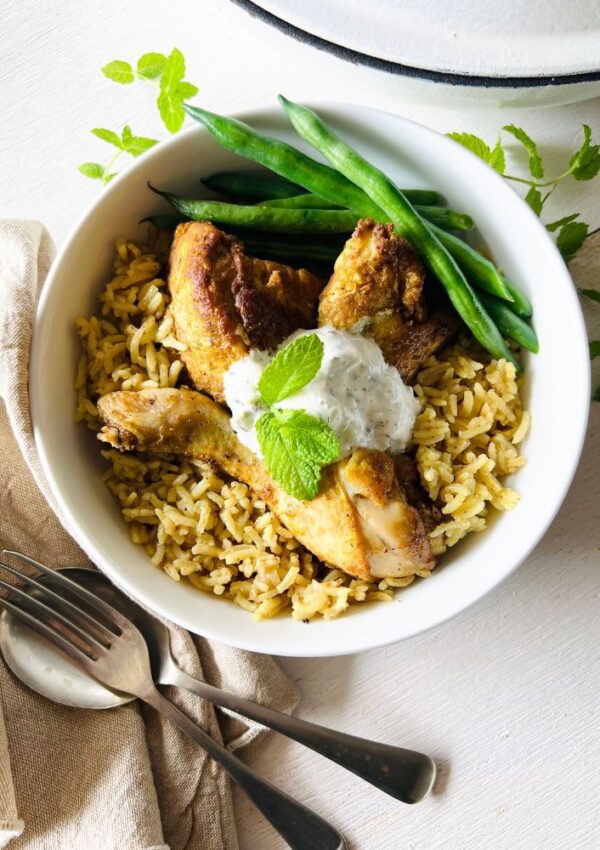 Curried Chicken & Rice in a bowl with mint leaves, napkin, fork
