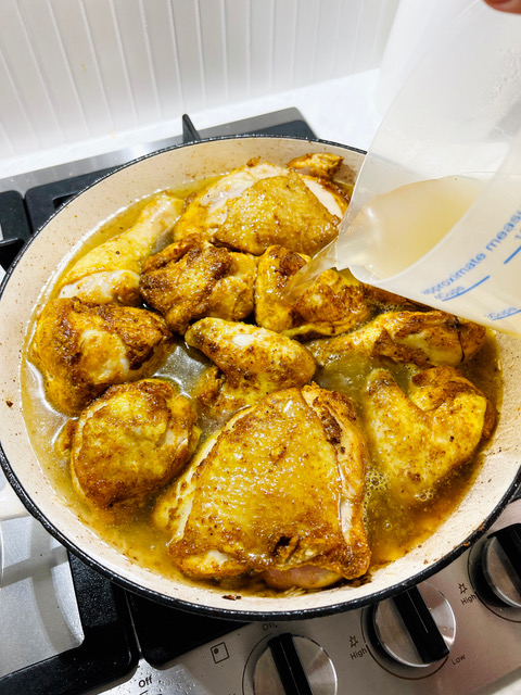 chicken in pan pouring over chicken stock