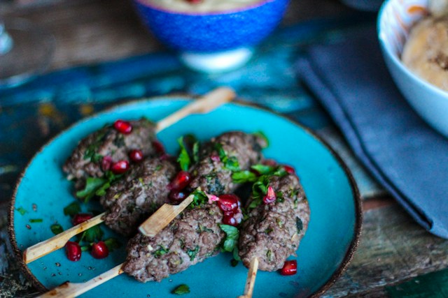 Lamb koftas on a blue plate with pomegrante seeds