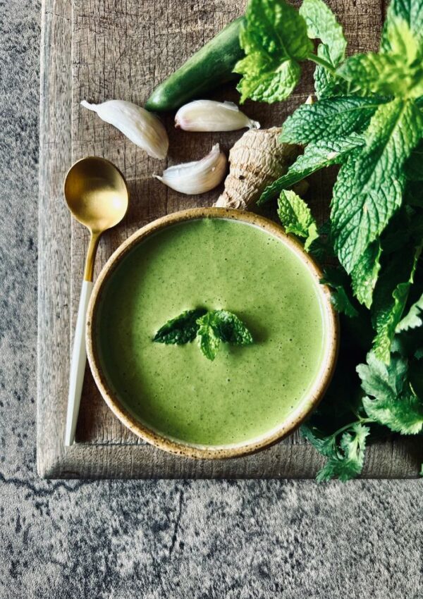 Indian Mint Chuntney in a bowl with herbs and garlic and spoon on marble background