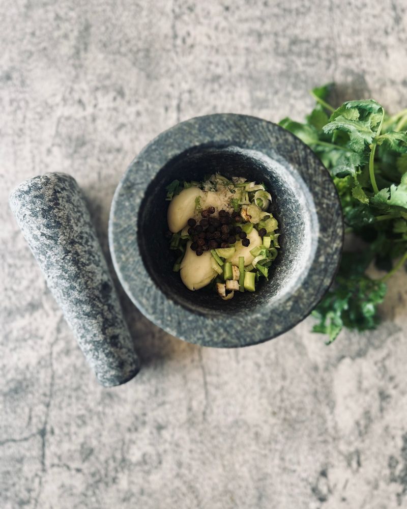mortar and pestle filled with garlic, coriander and pepper