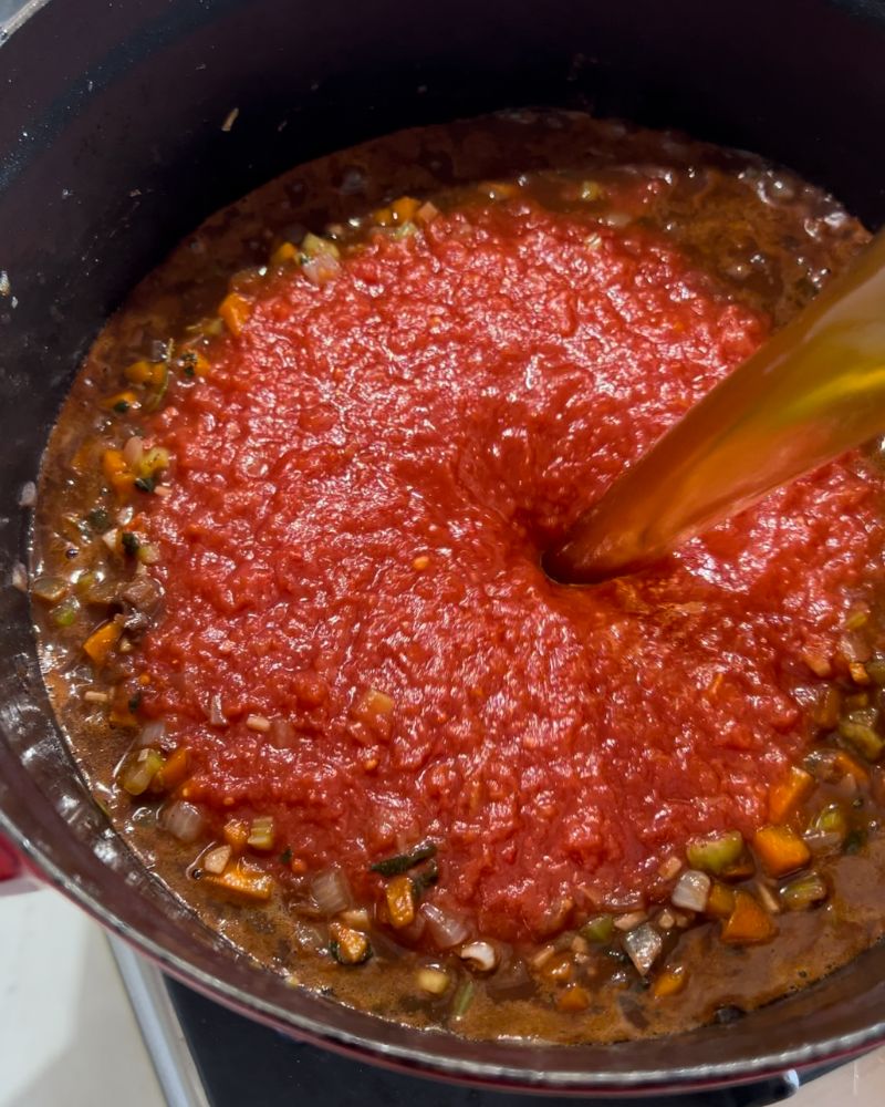 diced tomatoes in a pot and pouring in stock.
