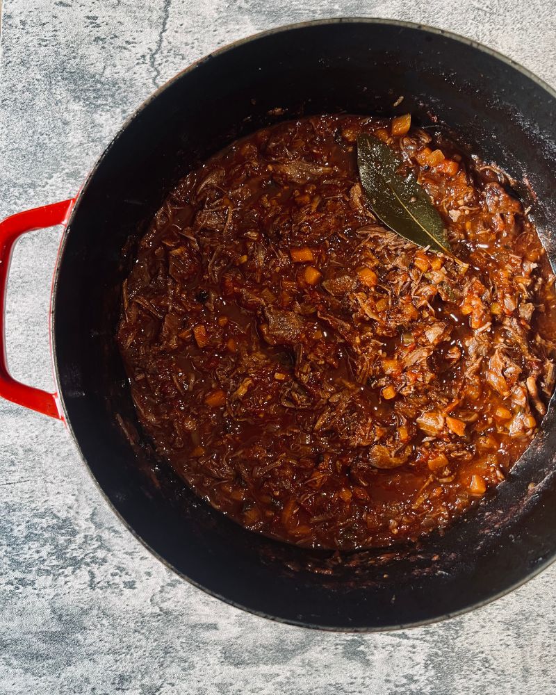 beef ragu in a pot on marble background