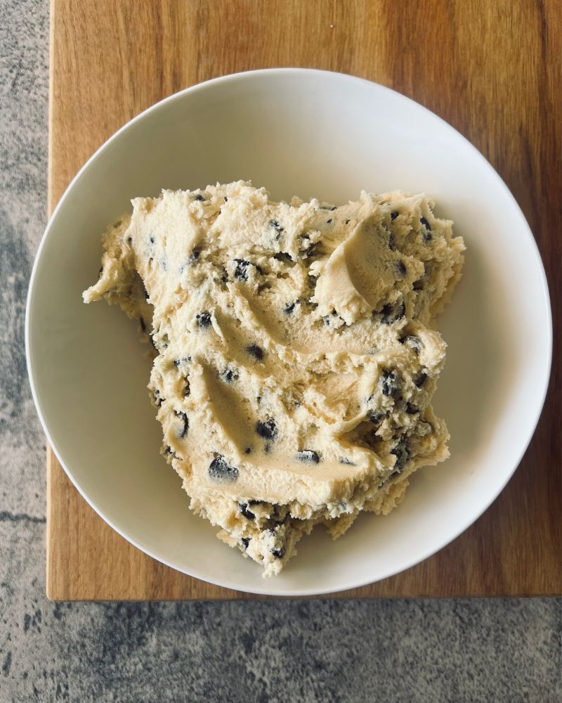 choc chop cookie dough in a white bowl on wooden board