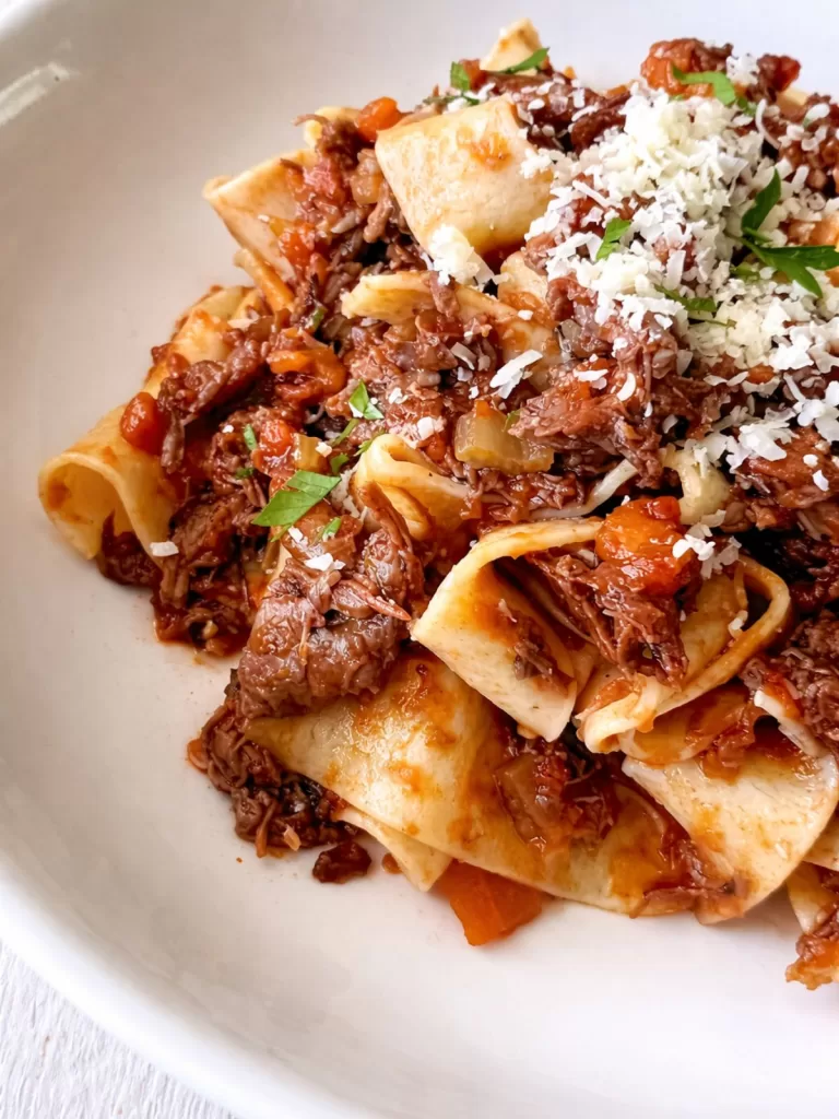 Beef shin ragu pasta topped with grated parmesan and herbs