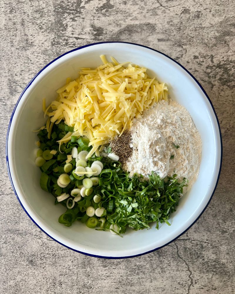grated cheese, shallots, flour and herbs in a white bowl