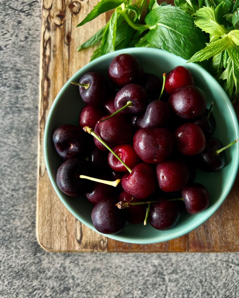 cherries in a green bowl with mint leaves