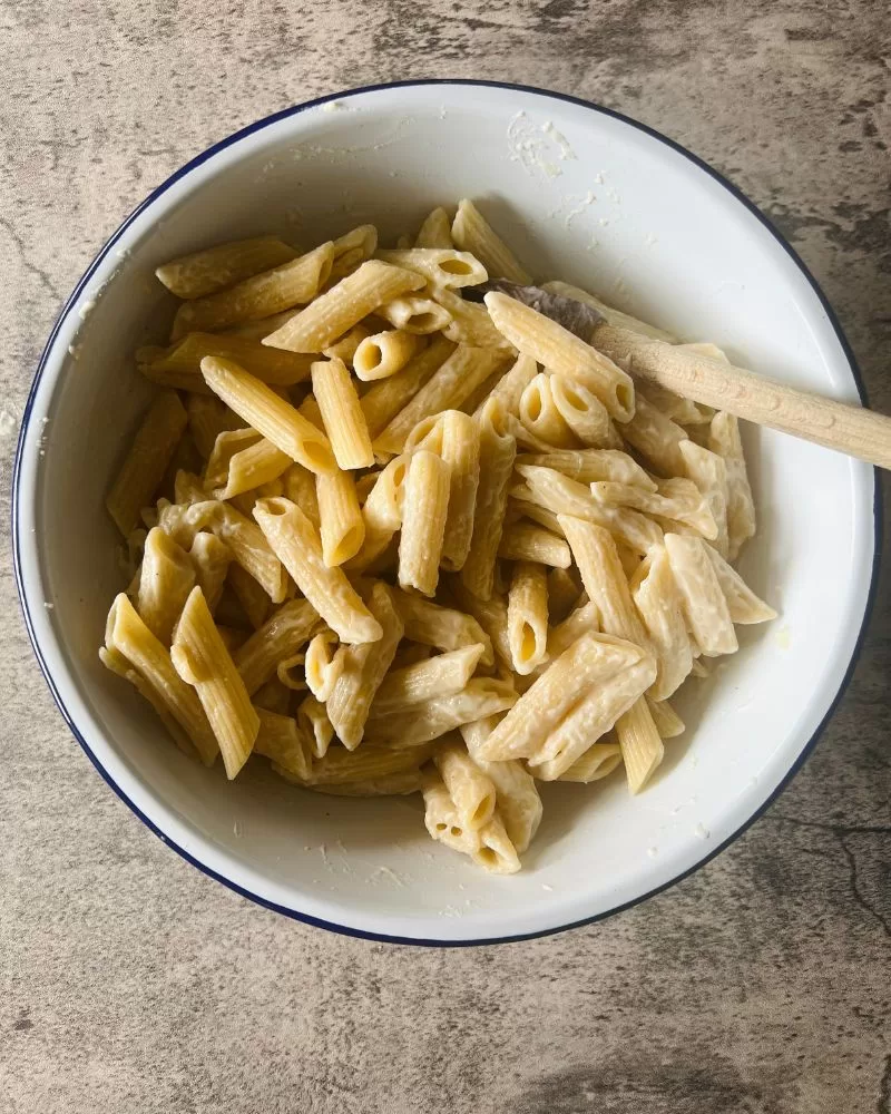 pasta in a mixing bowl with wooden spoon