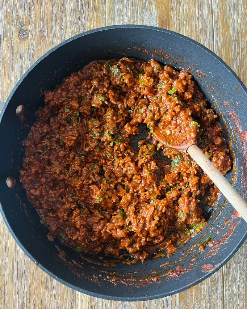 frypan with lamb mince mixture and a wooden spoon in it