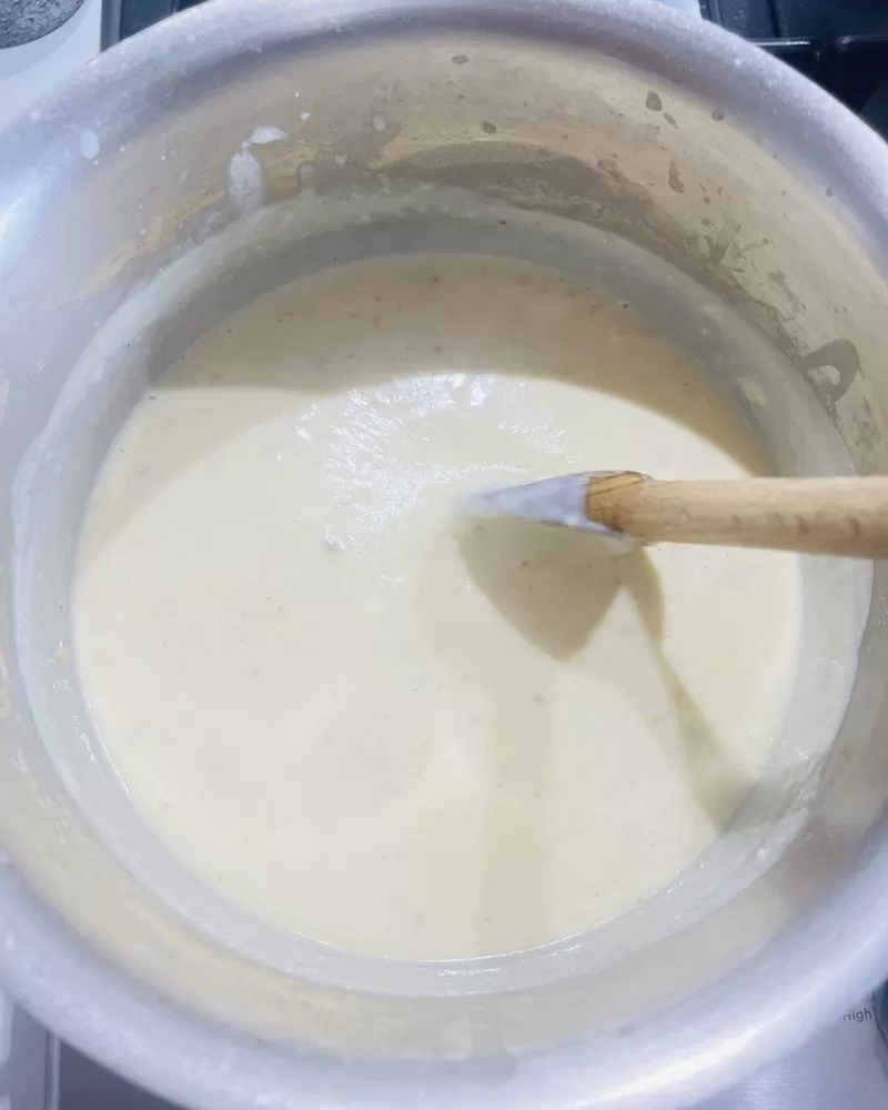 bechamel sauce in saucepan with wooden spoon