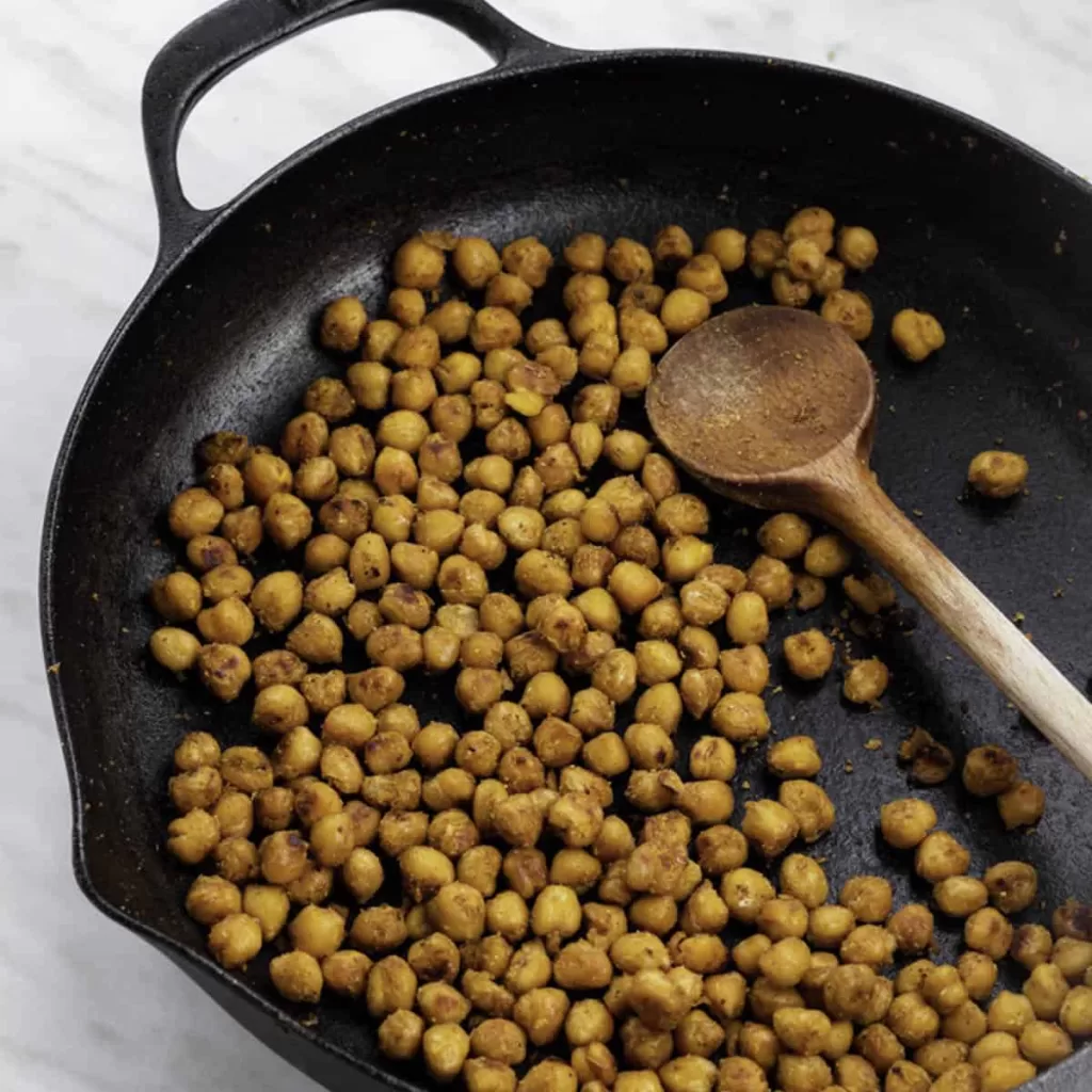 fry pan with chickpeas and spoon in it