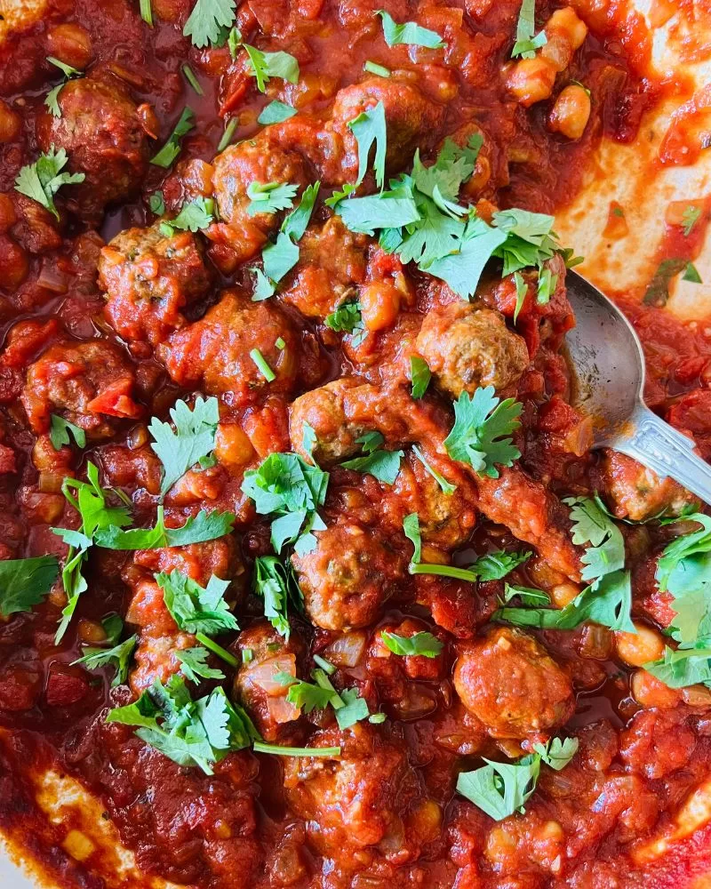 lamb meatball tagine in a pan with herbs scattered over