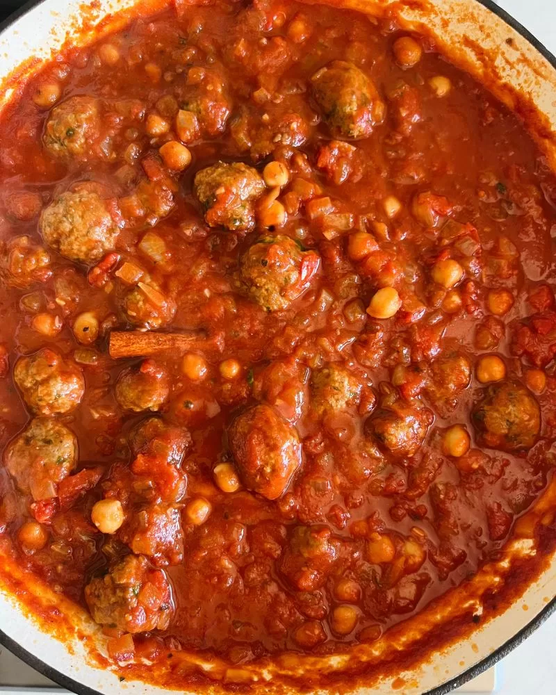 lamb meatballs with harissa and chickpeas cooking in a pan