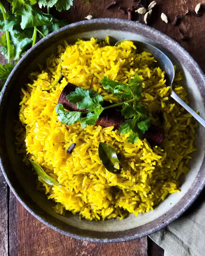 yellow rice in a bowl on dark wood background