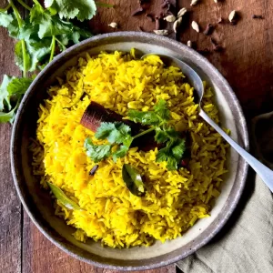 yellow rice in bowl with spoon and coriander