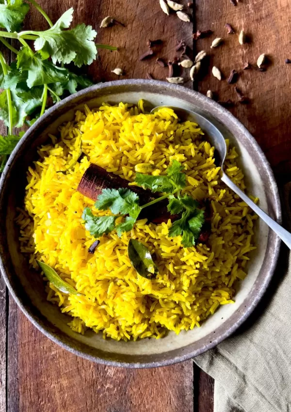yellow rice in bowl with spoon and coriander