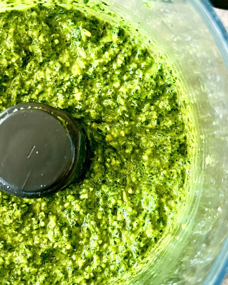 close up of basil pesto in food processor bowl