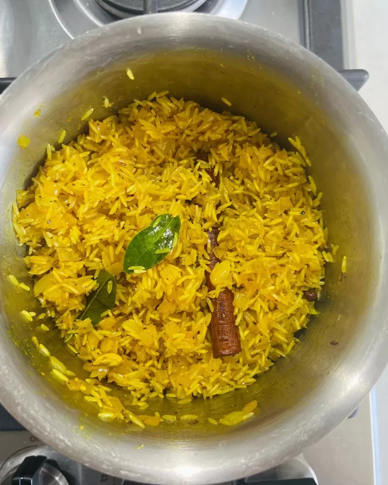 Cook Indian yellow rice in saucepan