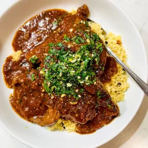 lamb stew in white bowl with couscous and fork
