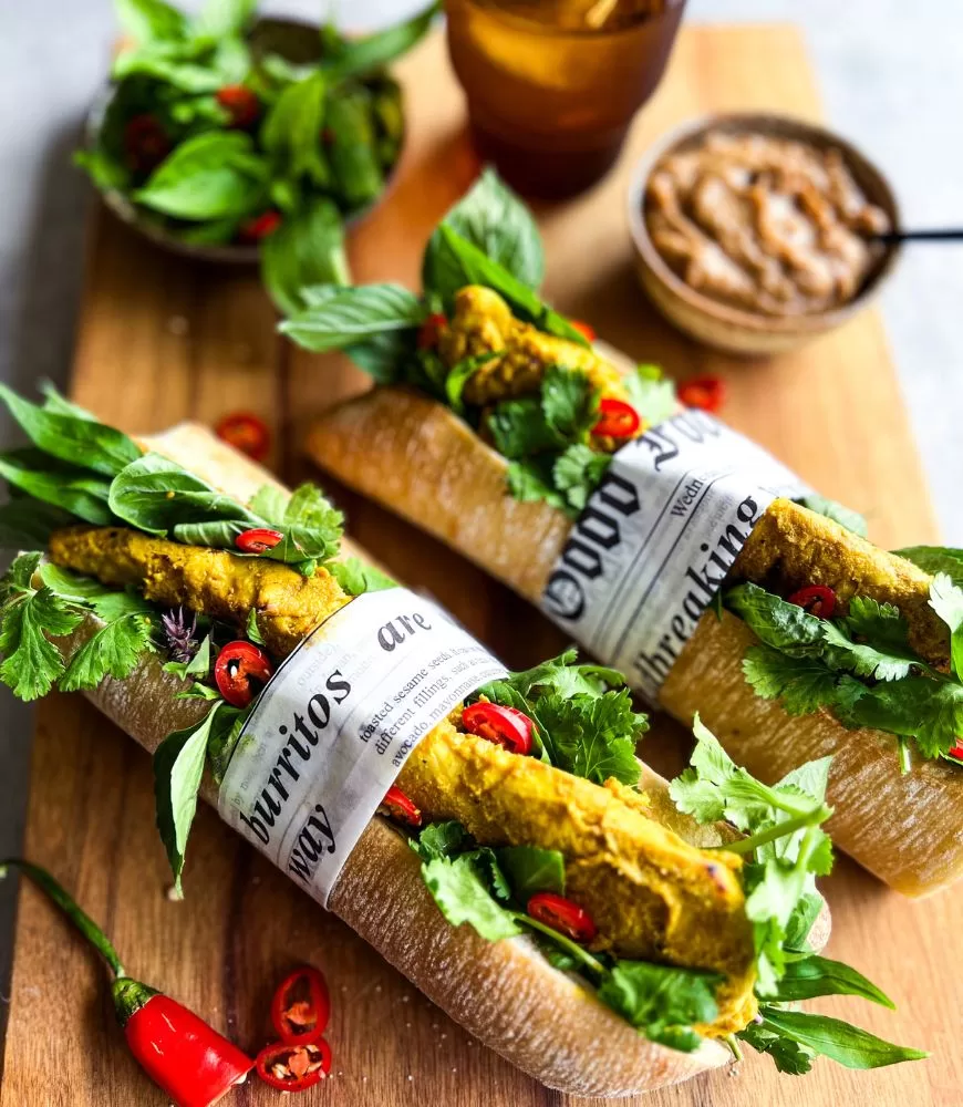 Thai Satay Chicken Baguettes on a wooden board with bowl of satay sauce