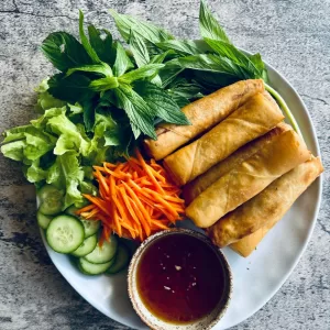 fried spring rolls on a plate with vegetables and dipping sauce