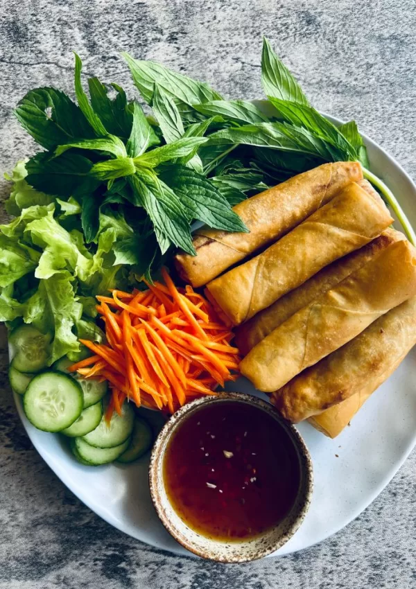 fried spring rolls on a plate with vegetables and dipping sauce