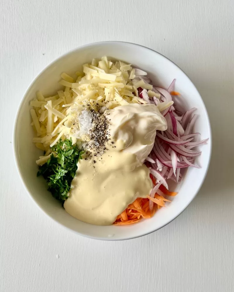 grated carrot, onion, cheese, parsley and mayonnaise in white bowl