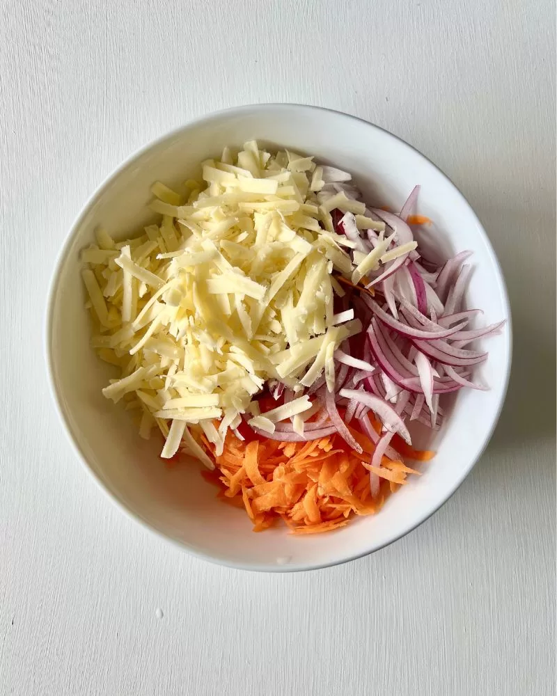 grated carrot, onion and cheese in white bowl