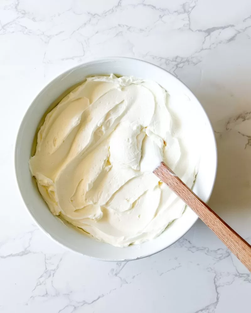 labneh with spoon in white bowl on marble background