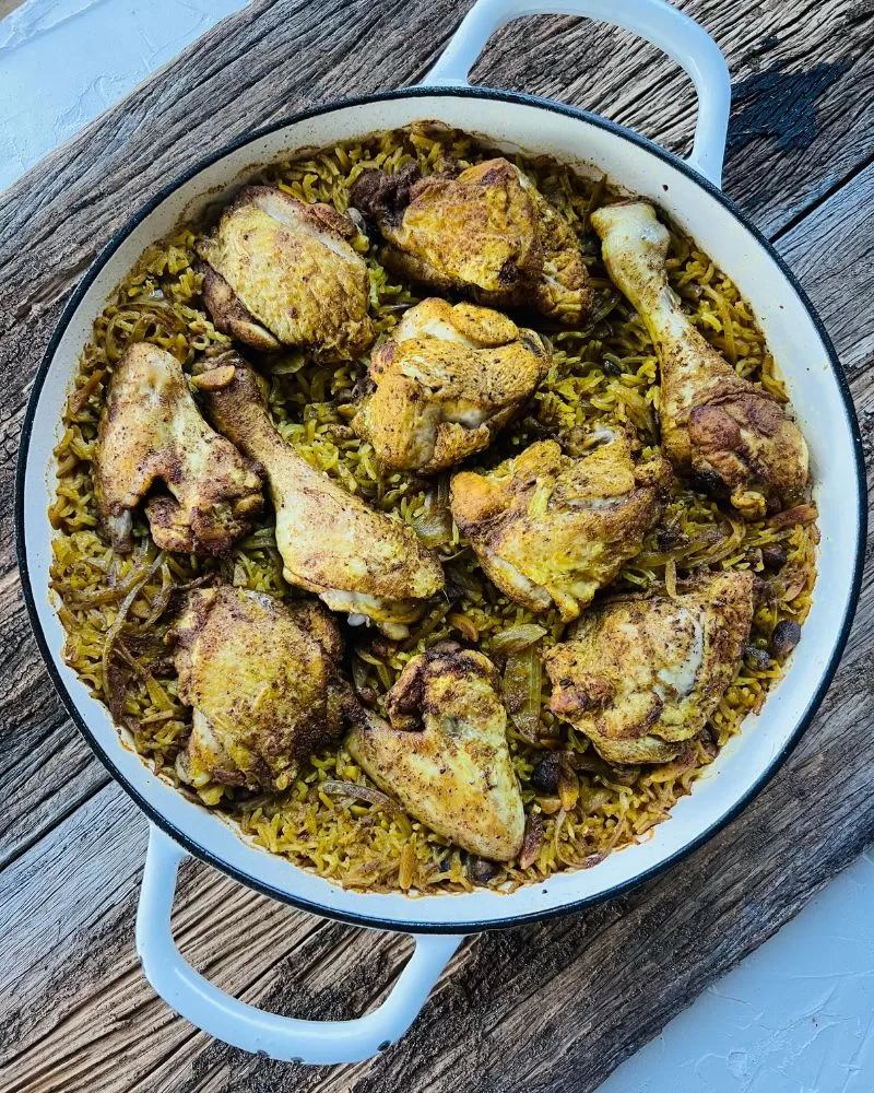 white pan with Middle Eastern chicken and rice on wood background