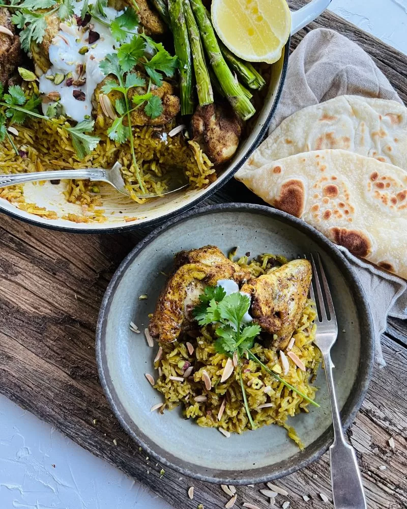 Middle Eastern Chicken and rice one pot in pan with bowl next to it with some in it along with flatbread