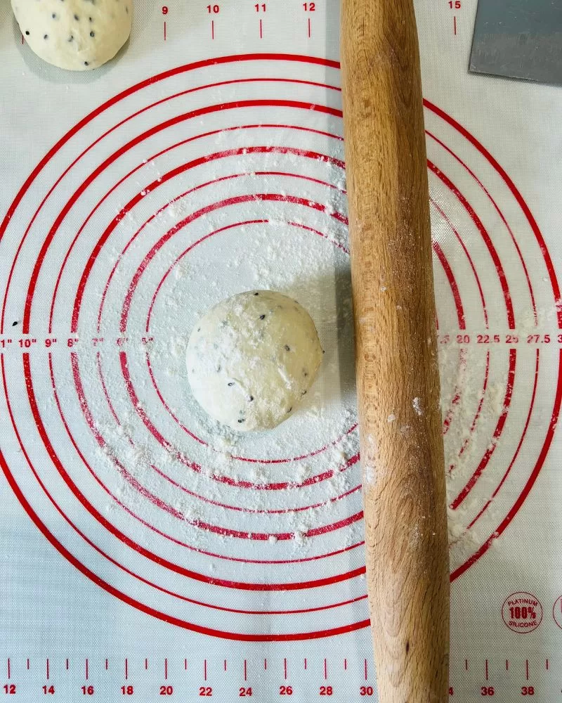 dough on a mat with rolling pin and flour