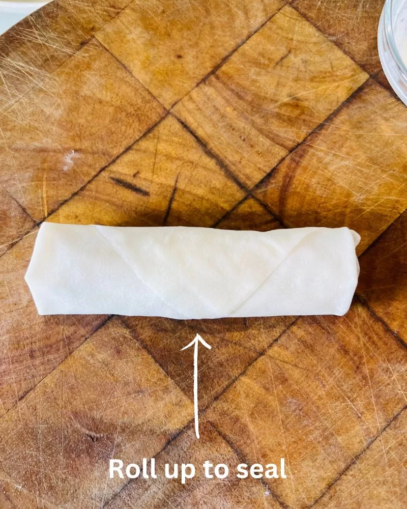 a rolled spring roll on wooden board
