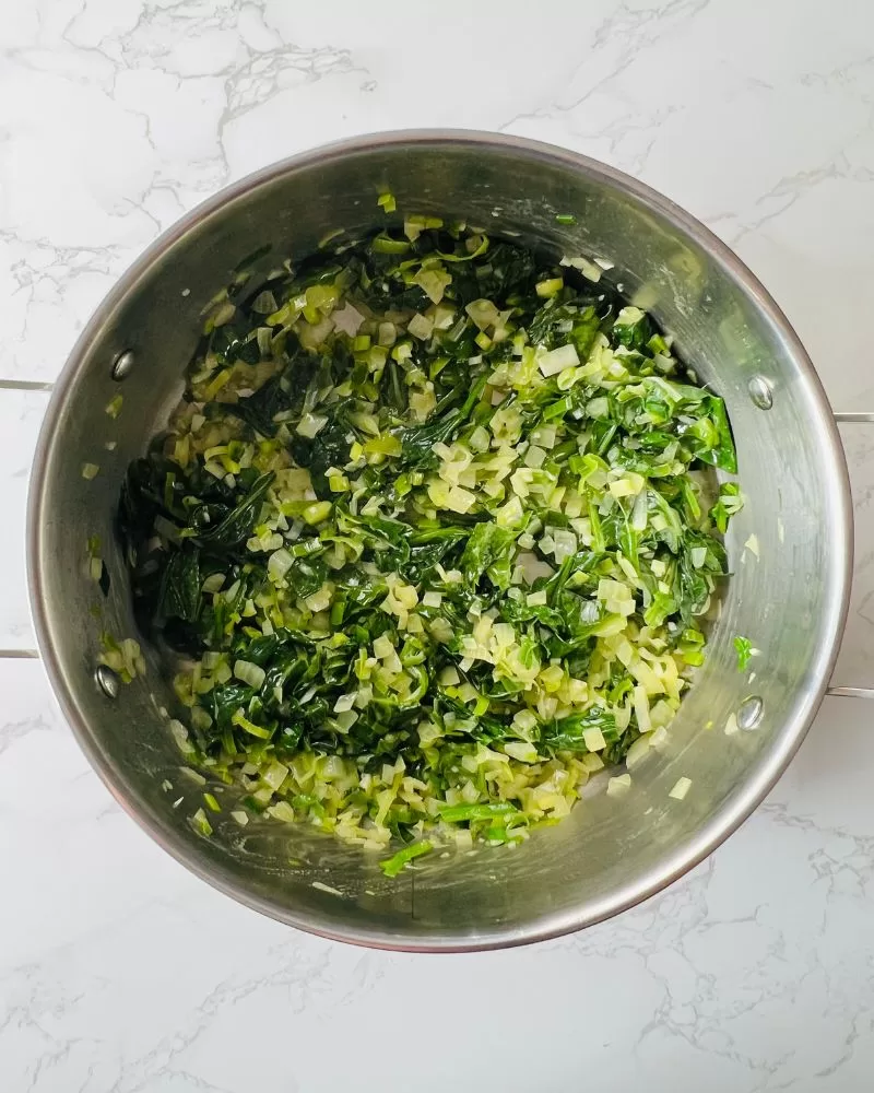 spinach, onion, and leek mixture in a saucepan