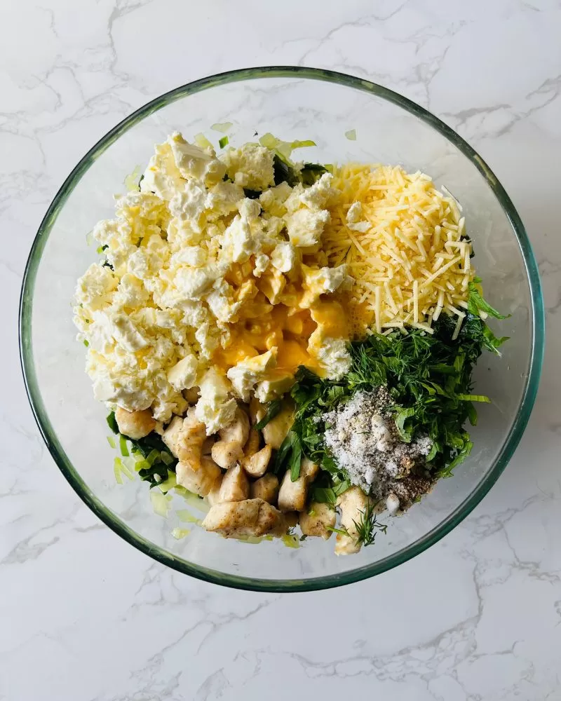 feta, cheese, chicken spinach in a glass bowl