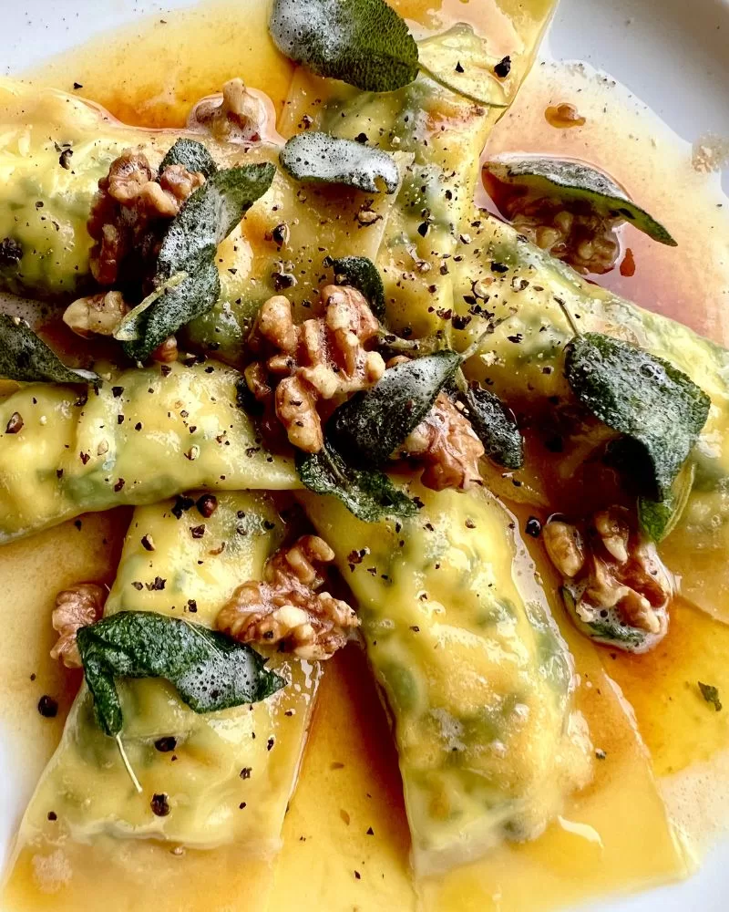 ravioli topped with burnt butter sauce, walnuts and sage