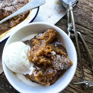 self saucing sticky date pudding in white bowl with ice cream