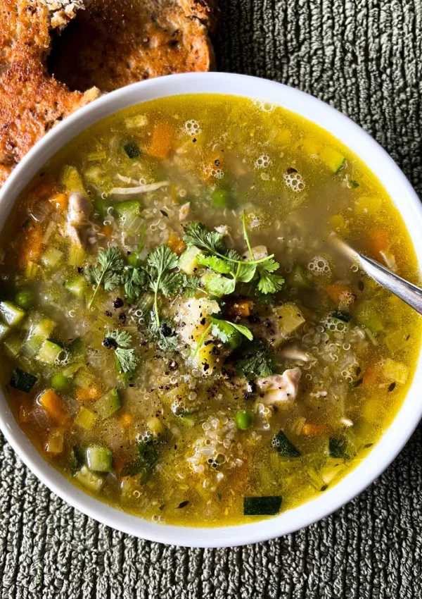 chicken & vegetable soup with quinoa in white bowl