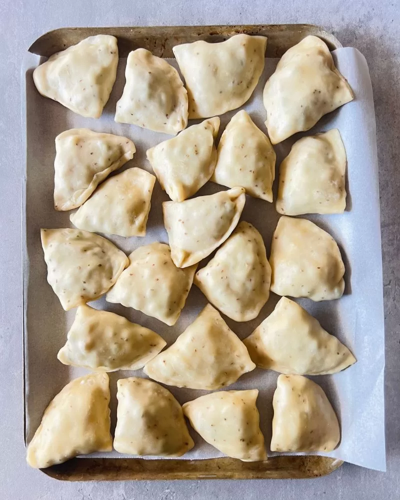 uncooked samosas on tray