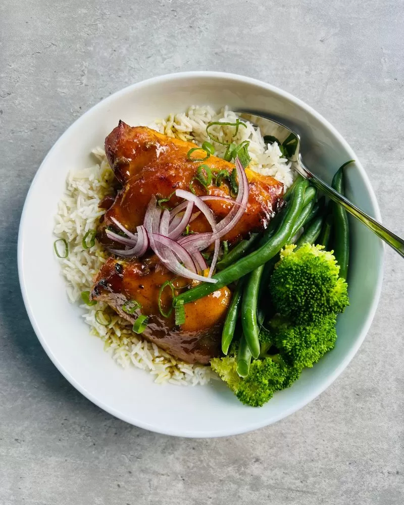 5 ingredient sticky curried honey chicken in white bowl, grey background