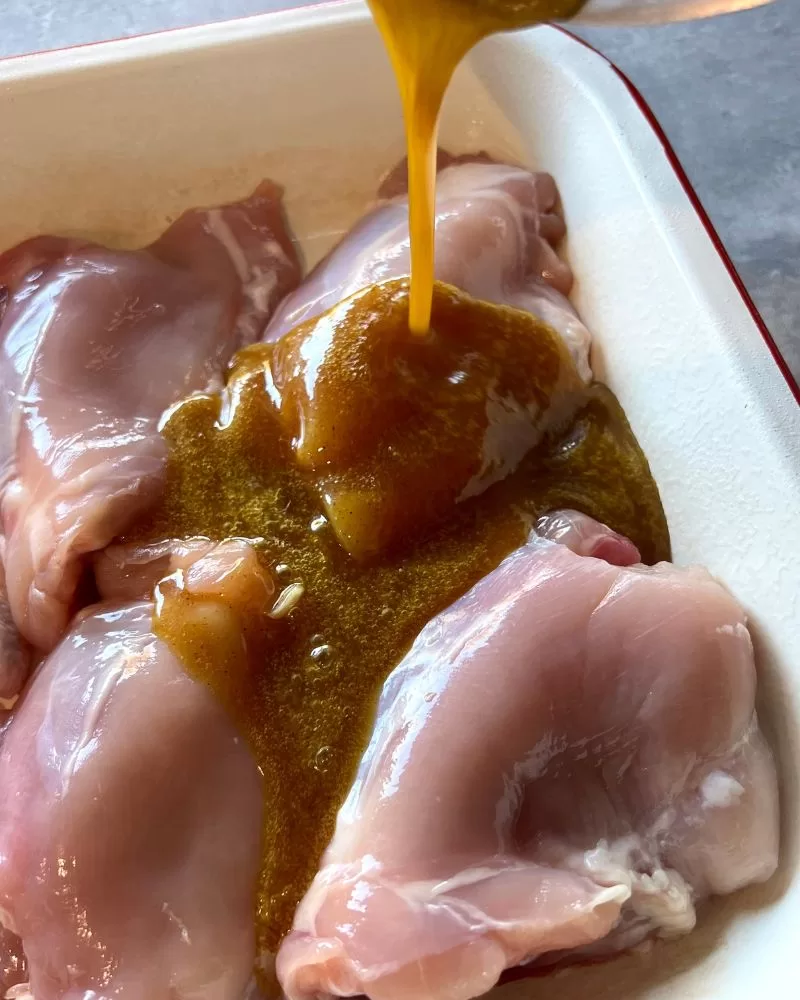 pouring sauce over raw chicken