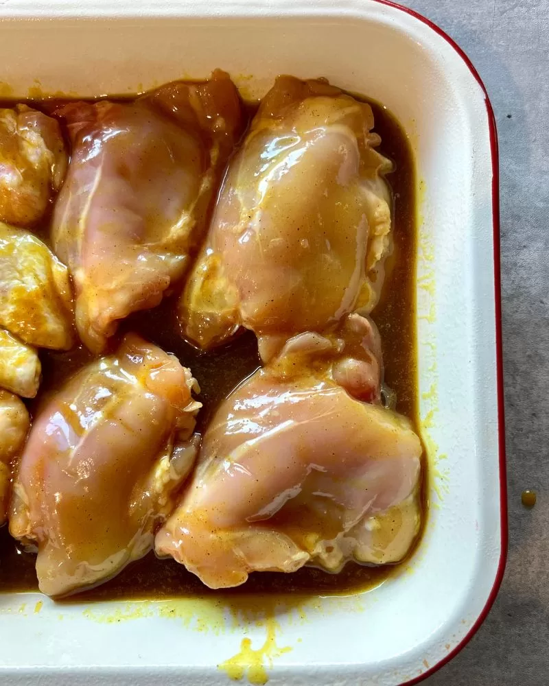 chicken with curry sauce in baking dish ready to go into the oven