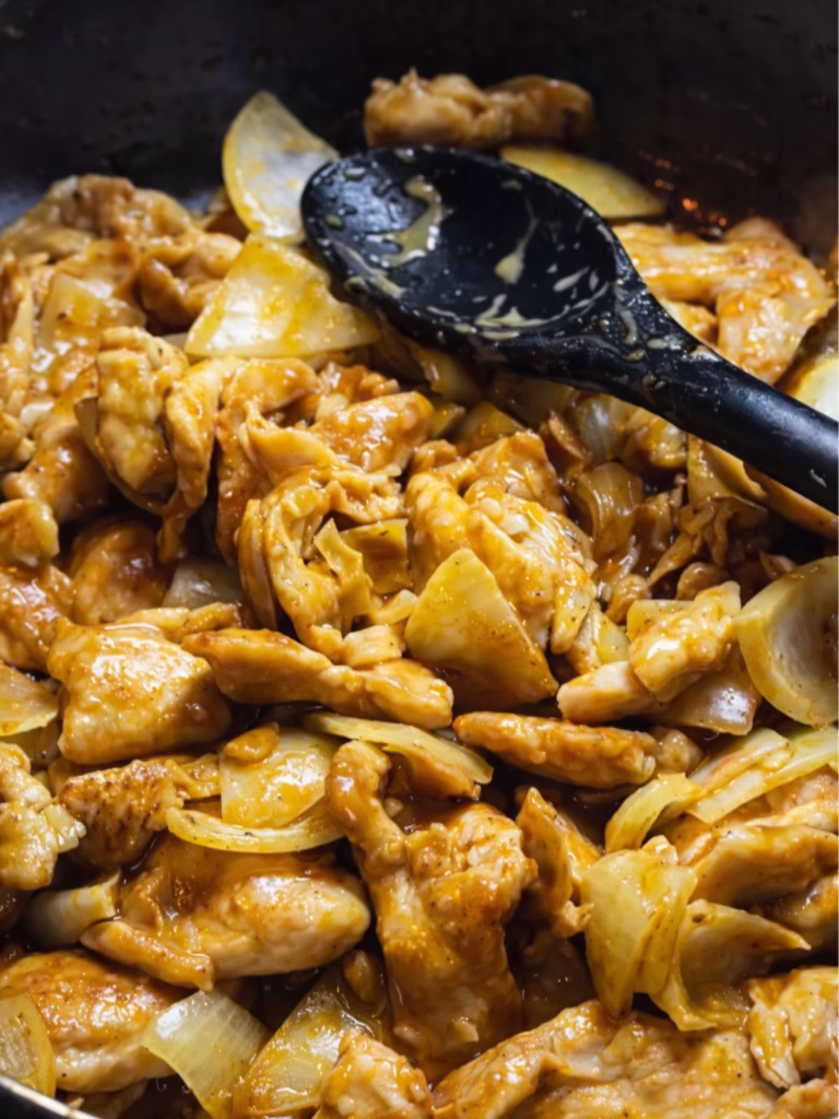 Satay chicken stir fry cooking in a pan with onion and peanut sate sauce