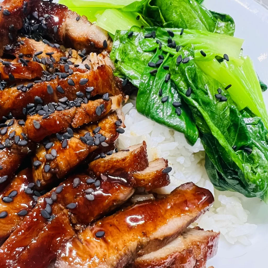 char siu pork with greens and topped with sesame seeds