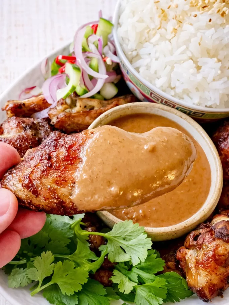 Satay chicken wing dipped into creamy peanut sauce