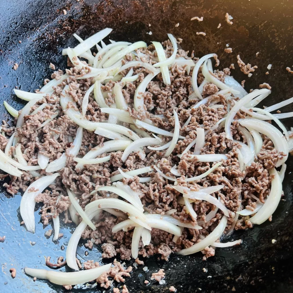 Beef mince cooking with sliced onions in a hot wok