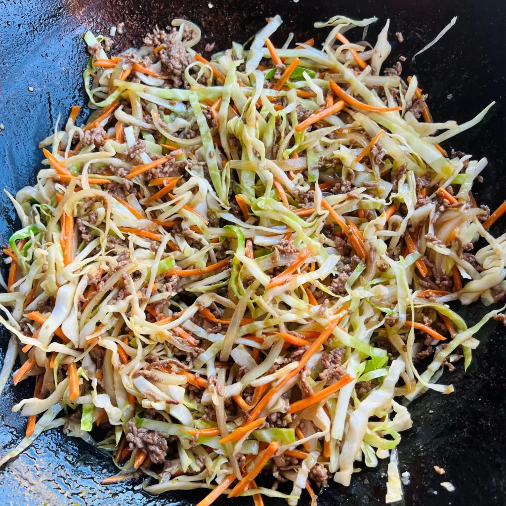 Beef mince and cabbage stir fry cooking in a wok